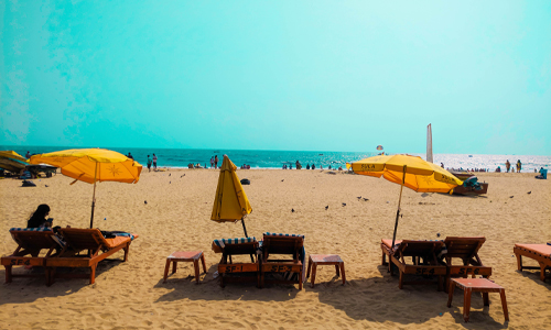 A serene beach scene with colorful umbrellas and chairs set up for relaxation and enjoyment.